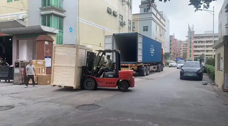 Forklift handling a wooden furniture crate beside an open container